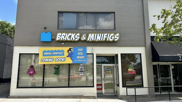 Exterior of the Bricks & Minifigs Uptown Minneapolis storefront, with its logo above the entrance and signs advertising LEGO buying, selling and trading.