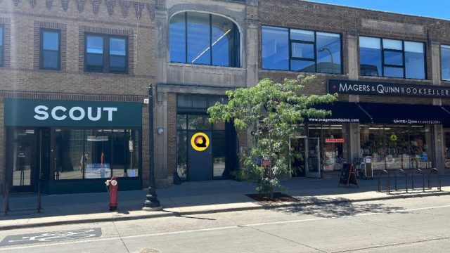 Uptown Minneapolis storefronts featuring Scout, a colorful storefront, and Magers & Quinn Booksellers along a tree-lined Hennepin Avenue sidewalk.